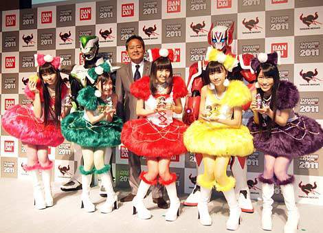 記者会見に登壇したメンバー。前列左から佐々木彩夏、有安杏果、百田夏菜子、玉井詩織、高城れに、後列左からワイルドタイガー、バンダイ代表取締役社長・上野和典、バーナビー・ブルックスJr. (C)ORICO